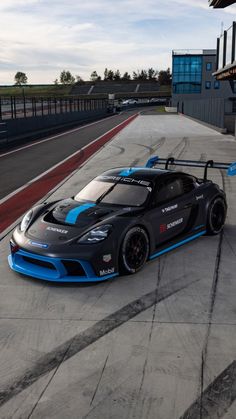 a black and blue race car parked on the side of a road next to a building