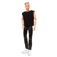 a male doll wearing black clothes and white shoes, standing on a white surface with his hands in his pockets