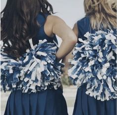 two girls in black and white cheerleaders with pom poms on their back