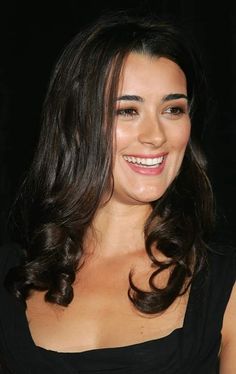 a woman with long dark hair smiling at the camera