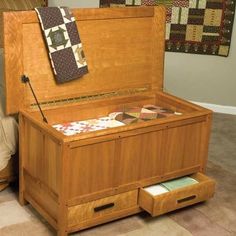 an open wooden chest with quilts on it