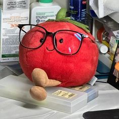 a red stuffed tomato with glasses on top of it's head sitting on a table