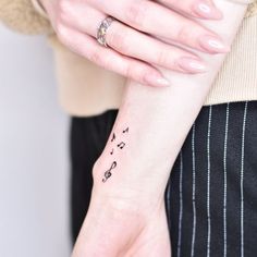 a woman's wrist with musical notes tattooed on the left side of her arm