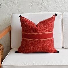 a red pillow sitting on top of a white couch