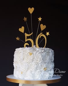 a cake with white frosting and gold stars on top is sitting on a stand