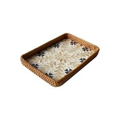 a wicker tray with black and white designs on the bottom, sitting on a white background