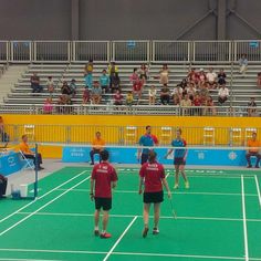 some people are playing tennis on a court with fans in the bleachers behind them