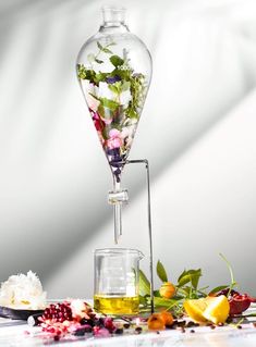 a glass vase filled with flowers on top of a table next to a flask