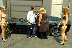 three women standing in front of a black sports car with two men talking to each other