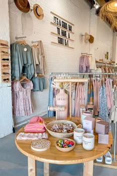 the inside of a clothing store with clothes hanging on racks and other items in bowls