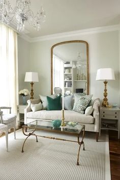 a living room filled with furniture and a chandelier above a glass coffee table