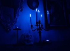 a blue lit room with candles in the corner and pictures on the wall behind it