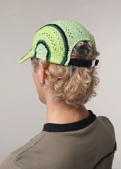 a man with curly hair wearing a green crochet hat