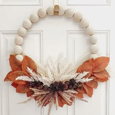 a white door with a wreath made out of dried leaves and other things hanging on it