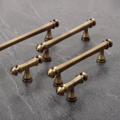 four antique style brass handles on a gray surface