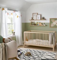 a baby's room with green walls and white furniture