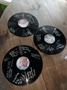 three black vinyl records with pictures of babies on them sitting on a wooden table top