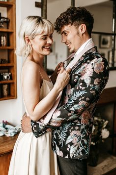 a man and woman standing next to each other in front of a mirror smiling at each other