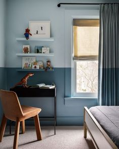 a bedroom with a bed, desk and shelves on the wall in front of a window