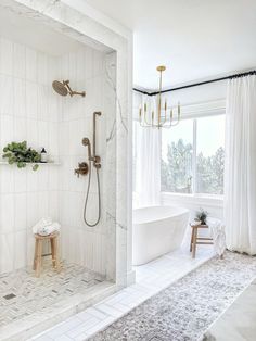 a white bathroom with a tub, shower head and rug on the floor next to it