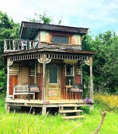 an old wooden house sitting on top of a lush green field