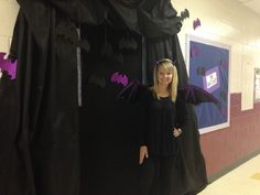 a woman standing in front of a black curtain with bats on it and purple curtains behind her