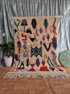 an old rug is displayed on a wooden floor next to a potted plant and other decorative items