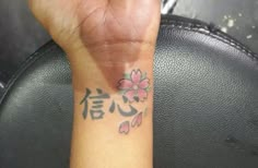 a person's hand with a flower tattoo on it and the word love written in chinese