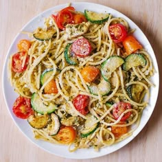 a plate of pasta with zucchini and tomatoes