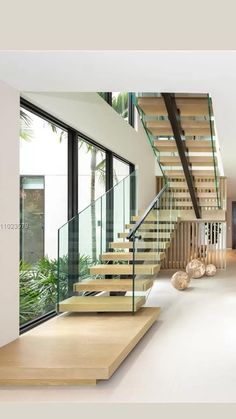 a staircase with glass railing and wooden handrails in a modern home setting,