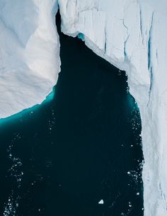 an iceberg is seen from above with water in the foreground and snow on the far side