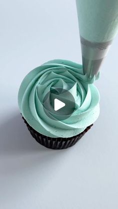 a cupcake being frosted with blue icing