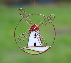 a glass ornament with a red bow on it's top and a windmill in the middle