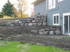 a large rock wall next to a house