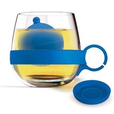 a glass with a tea ball in it next to a blue lid