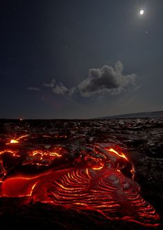 the moon shines brightly in the sky above lava and water on an island at night