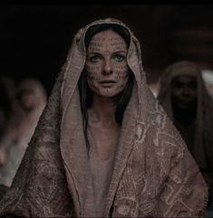 a woman with face paint on her head and veil over her head, surrounded by other people