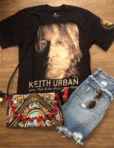 a t - shirt, jeans and purse are laid out on the floor