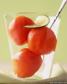 three oranges in a glass with a spoon on the side and lime slices around them