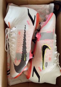 a pair of white and pink nike shoes in a box with the shoe laces still attached