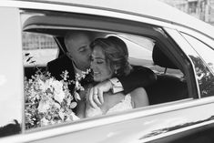 a bride and groom kissing in the back seat of a car with flowers on it