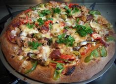 a pizza sitting on top of a pan covered in cheese and toppings with green peppers