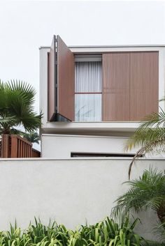 an apartment building with wooden shutters and palm trees in the foreground on a cloudy day