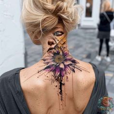 a woman's back neck with a flower tattoo on the upper part of her neck