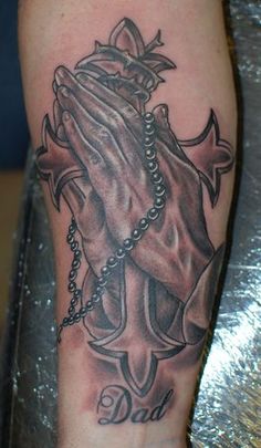 a black and grey tattoo on the arm of a person with a rosary in it