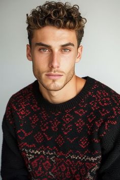 a young man with curly hair wearing a black and red sweater looking at the camera