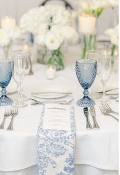 the table is set with silverware and white flowers