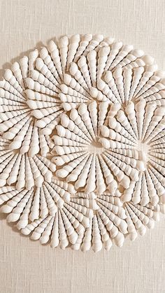 an intricately designed wall hanging made out of white wood planks on a beige linen background