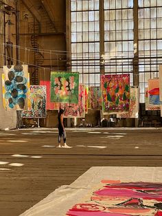 a person standing in an open area with paintings on the wall and windows behind them