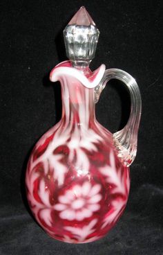 a red and white glass vase sitting on top of a table